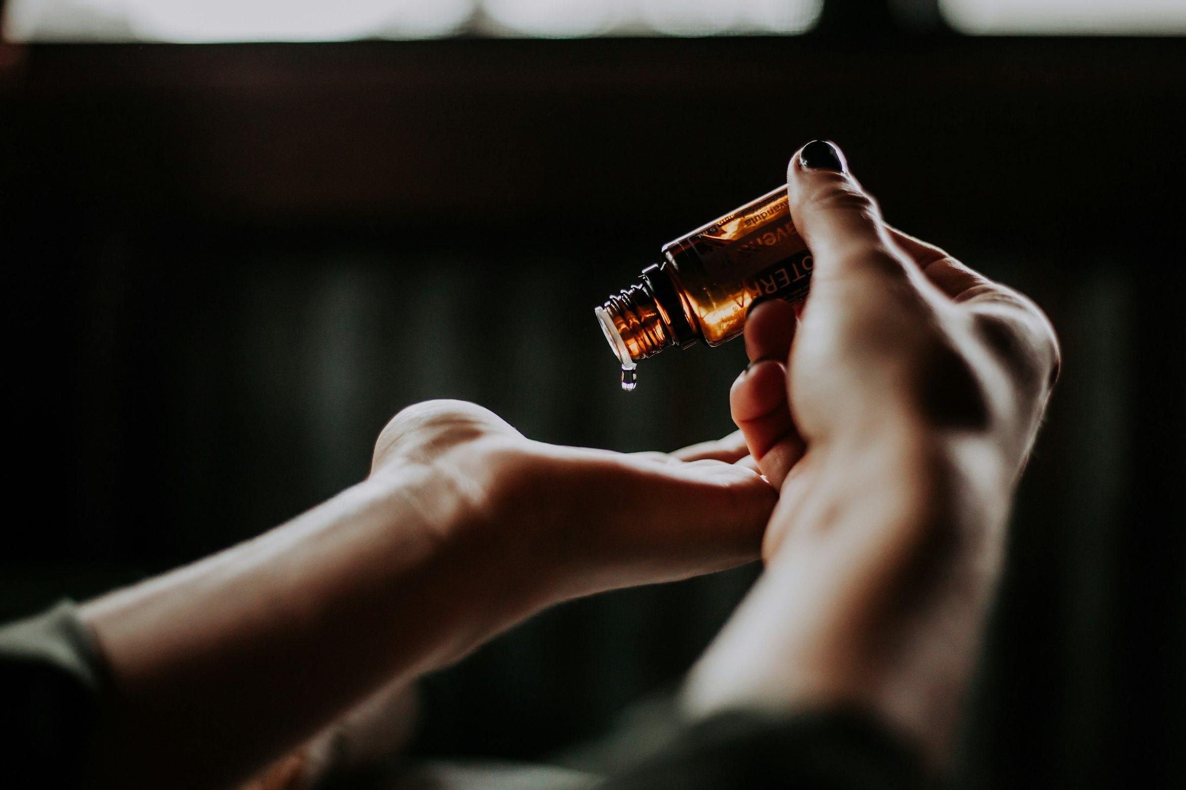 Drops of oil falling from a small bottle into a palm